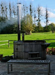 ein holzbefeuerter Grill in einem Park mit einer Bank in der Unterkunft Huis van luut in Tielt