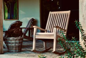 un fauteuil à bascule assis sur une terrasse couverte à côté d'un panier dans l'établissement Huis van luut, à Tielt
