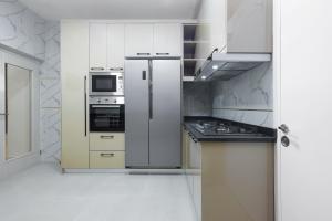 a kitchen with white cabinets and a stainless steel refrigerator at BKT Cribs - Apartments & Suites in Abuja