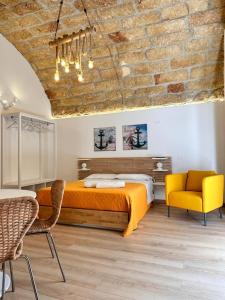 a bedroom with an orange bed and two chairs at I Faraglioni Comfort Rooms in Terrasini