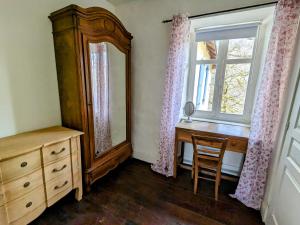 a bedroom with a dresser and a mirror and a window at Sous le Chateau in Jumilhac-le-Grand