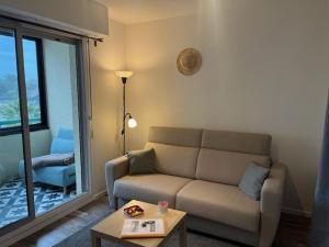 ein Wohnzimmer mit einem Sofa und einem Tisch in der Unterkunft Horizon Océan 1 - Superbe appartement 2 pièces avec parking privatif in Capbreton