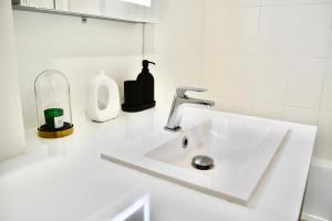 - un lavabo blanc dans la salle de bains avec un distributeur de savon dans l'établissement 5-Min Paris, Lovely Eco Brand-New Sun-Bathed Apt !, à Aubervilliers
