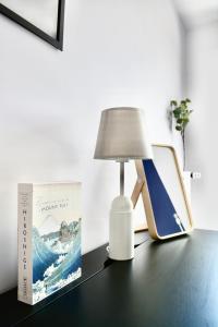 a lamp sitting on a desk next to a book at 5-Min Paris, Lovely Eco Brand-New Sun-Bathed Apt ! in Aubervilliers