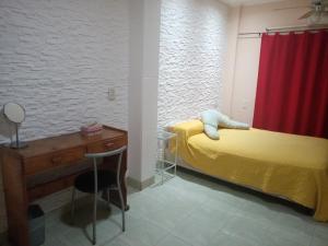 1 dormitorio con cama amarilla y cortina roja en LOURDES en Yerba Buena