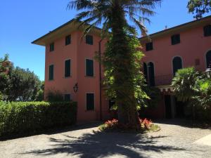 een roze huis met een palmboom ervoor bij Appartamenti sul mare Villa il Fortullino in Case Fortullino