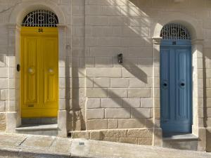 due porte gialle e blu sul lato di un edificio di Typical Maltese Maisonette in St.Julians a San Giuliano