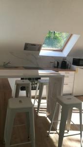 a kitchen with white stools and a counter with a window at le beau coin, unique et magique 