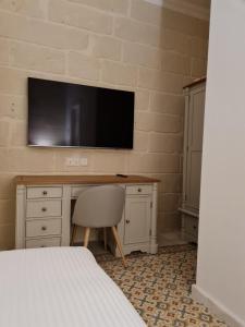 a bedroom with a desk with a television on a wall at Typical Maltese Maisonette in St.Julians in St. Julianʼs