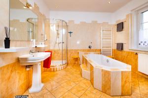ein Bad mit einer Badewanne, einem Waschbecken und einer Dusche in der Unterkunft Ferienwohnung ALEX in Burgau