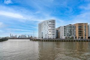 un edificio alto junto a un río con edificios en Large 2Bed 2Bath Apartment Beautiful River Views London Greenwich Cutty Sark, en Londres