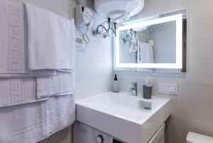ein weißes Badezimmer mit einem Waschbecken und einem Spiegel in der Unterkunft MYFREEDOM Апартаменти Залізничний Вокзал in Kiew