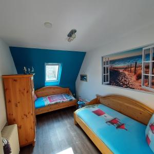 2 camas en una habitación con paredes azules en Ferienwohnungen im Haus Ankerplatz, en Esens
