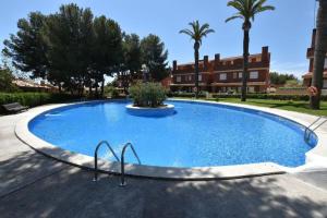 einem großen blauen Pool mit Palmen und einem Gebäude in der Unterkunft Preciosa zona natural La Mora in Tarragona