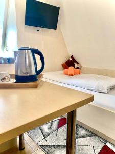 uma chaleira de chá sentada numa mesa ao lado de uma cama em M-Hotel em Estugarda