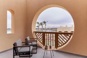 een kamer met een balkon met stoelen en een rond raam bij Steigenberger Golf Resort El Gouna in Hurghada