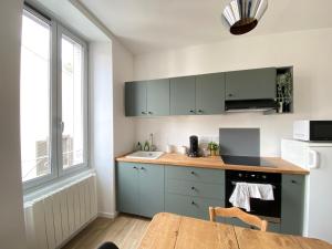 a kitchen with green cabinets and a wooden table at Le Vichatel - Charmant T3 en centre ville proche de place Gaillard in Clermont-Ferrand