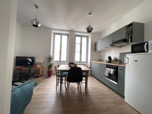 uma cozinha e sala de jantar com mesa e frigorífico em Le Vichatel - Charmant T3 en centre ville proche de place Gaillard em Clermont-Ferrand