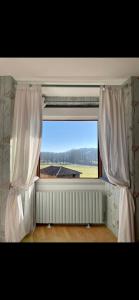a window with white curtains and a view of a field at L’observatoire in Solignac