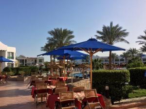 a patio with tables and chairs with blue umbrellas at Panorama Naama Heights in Sharm El Sheikh