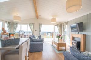 a living room with a couch and a tv at Luxury family Beechwood lodge with hot tub in Lochwinnoch