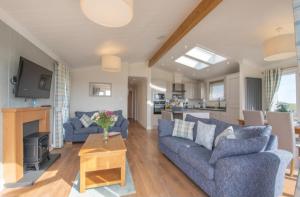 ein Wohnzimmer mit 2 blauen Sofas und einem Tisch in der Unterkunft Luxury family Beechwood lodge with hot tub in Lochwinnoch