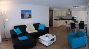 a living room with a black couch and blue chairs at Haus Aida, Bettmeralp in Bettmeralp