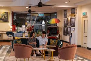 a man and woman sitting on chairs in a room at Armenian Street Heritage Hotel in George Town