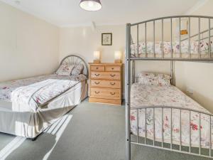 a bedroom with two bunk beds and a dresser at Rose Cottage in Pembrey