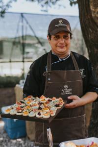 a man in an apron holding a tray of sushi at El Colibri - Relais & Châteaux in Santa Catalina