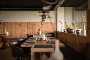 un ristorante con un lungo tavolo e sedie in legno di Green Luxury Hotel Pfösl a Nova Ponente