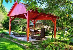 a red pavilion in a garden with a table and bench at Kis-Balatoni Ökoporta in Zalaszabar