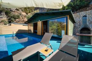 una piscina con 2 sillas y una casa en Villa Kabak, en Fethiye