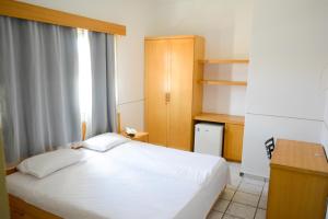a bedroom with a white bed and a desk at Hotel Villa Real in Sobral