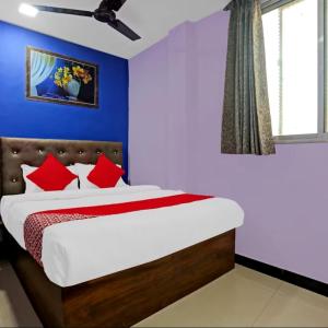- un lit avec des oreillers rouges dans une chambre bleue dans l'établissement Hotel Welcome Inn,Mumbai, à Mumbai