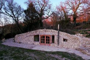 a small stone house in a stone wall at Maison Terre Les Cabanes de Fallot in LʼIsle-Bouzon