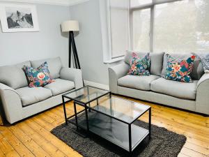 uma sala de estar com 2 sofás e uma mesa de café em vidro em Horsforth Lodge em Horsforth