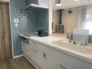 a kitchen with a sink and a blue tile wall at Permai Japon in Nikko