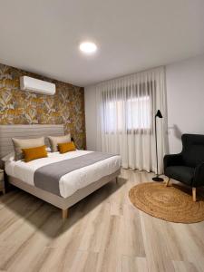 a bedroom with a large bed and a chair at Apartamentos Doña Emilia in Adeje