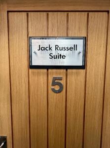 Uma porta de madeira com uma placa que diz Jack Russell Suite. em The Dog Inn em Longridge