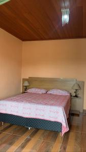 a bedroom with a bed with a red bedspread and two lamps at Jeitinho da Sô in Tiradentes