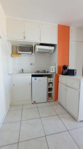 una cocina con armarios blancos y una pared de color naranja en Monoambiente Chiverta, en Punta del Este