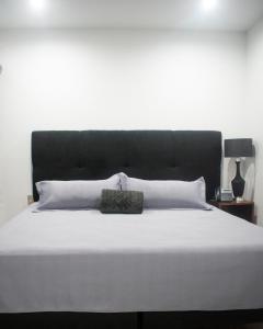 een groot bed met een zwart hoofdeinde en witte kussens bij Hotel Manadia in Tequila