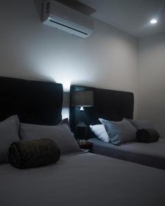 een slaapkamer met 2 bedden met kussens en een lamp bij Hotel Manadia in Tequila