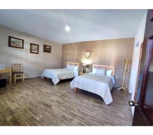 a bedroom with two beds and a table and a desk at Hotel Casa Francisca Mazamitla. in Mazamitla