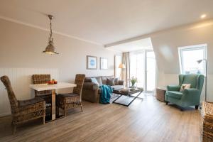 a living room with a couch and a table and chairs at Weisse Villa Apartment 3 2 Annis Strandnest in Büsum