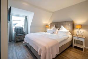 a bedroom with a large white bed and a chair at Weisse Villa Apartment 3 2 Annis Strandnest in Büsum