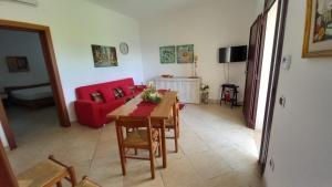 sala de estar con mesa y sofá rojo en Casa Domenica, en Torre Lapillo