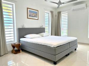 a bed in a bedroom with white walls and windows at Villa Leoni Curaçao in Willemstad +19 photos