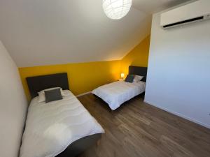 two beds in a room with yellow walls at SCI BSA Magnifique maison au calme in Les Essards-Taignevaux